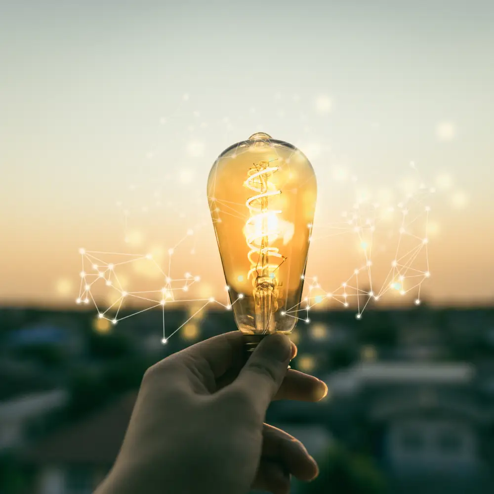 Main tenant une ampoule allumée au crépuscule